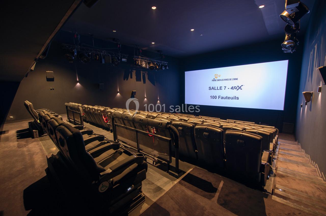 Salle de cinéma équipée de fauteuils inclinables, écran large et projecteurs, avec 100 places disponibles.