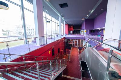 Miniature Location salle Caen (Calvados) - Pathé Les Rives de l'Orne #15 Intérieur d'un bâtiment moderne avec escalier, rambardes en métal, murs colorés et grandes baies vitrées.
