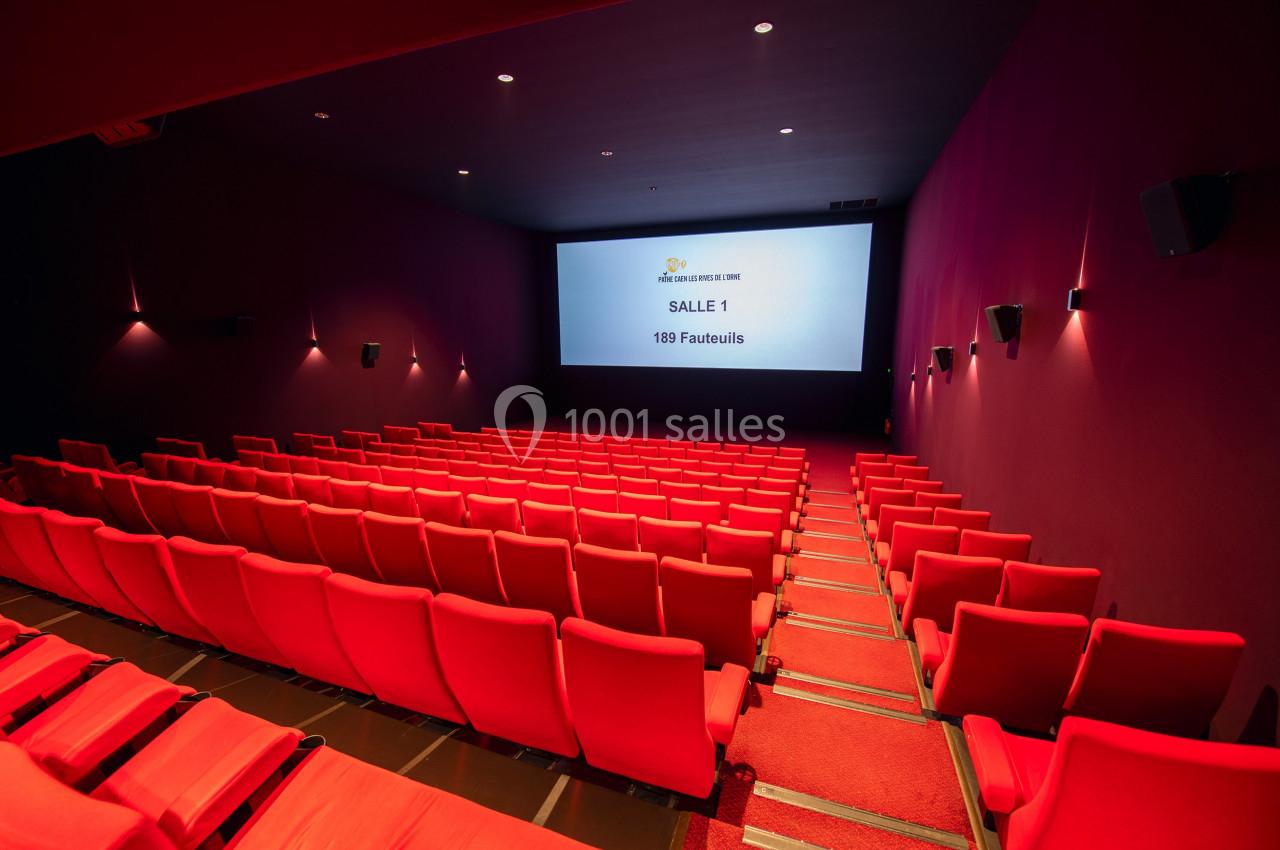Salle de cinéma vide avec des rangées de fauteuils rouges et un écran affichant ’Salle 1 - 189 fauteuils’.