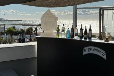 Salle de restaurant lumineuse avec tables dressées, chaises noires et blanches, et terrasse extérieure avec vue sur des…