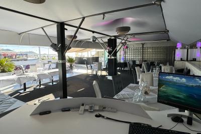 Salle de restaurant lumineuse avec tables dressées, chaises noires et blanches, et terrasse extérieure avec vue sur des…