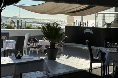 Salle de restaurant lumineuse avec tables dressées, chaises noires et blanches, et terrasse extérieure avec vue sur des…