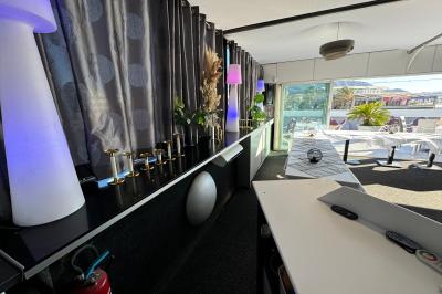 Salle de restaurant lumineuse avec tables dressées, chaises noires et blanches, et terrasse extérieure avec vue sur des…