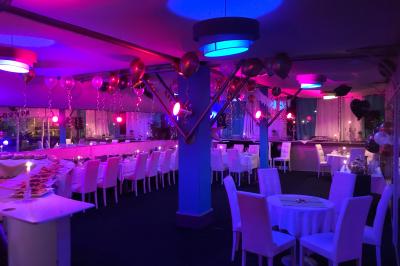 Salle de restaurant lumineuse avec tables dressées, chaises noires et blanches, et terrasse extérieure avec vue sur des…