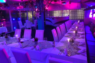 Salle de restaurant lumineuse avec tables dressées, chaises noires et blanches, et terrasse extérieure avec vue sur des…