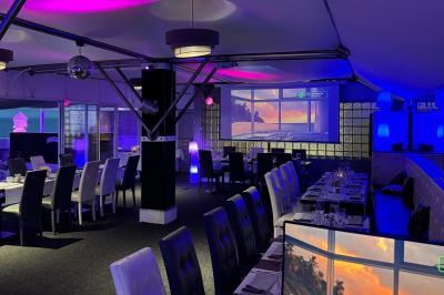 Salle de restaurant lumineuse avec tables dressées, chaises noires et blanches, et terrasse extérieure avec vue sur des…