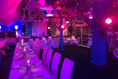 Salle de restaurant lumineuse avec tables dressées, chaises noires et blanches, et terrasse extérieure avec vue sur des…