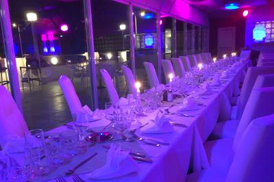 Salle de restaurant lumineuse avec tables dressées, chaises noires et blanches, et terrasse extérieure avec vue sur des…