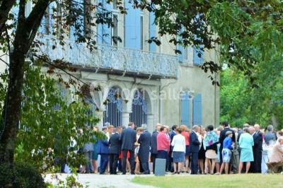 Des personnes en tenue blanche brandissent des cierges magiques lors d'un dîner en plein air devant un bâtiment éclairé.