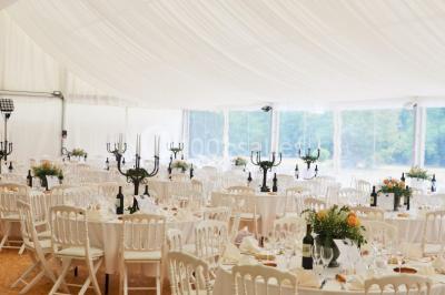 Des personnes en tenue blanche brandissent des cierges magiques lors d'un dîner en plein air devant un bâtiment éclairé.