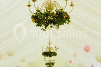 Des personnes en tenue blanche brandissent des cierges magiques lors d'un dîner en plein air devant un bâtiment éclairé.