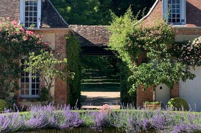 Miniature Location salle Triguères (Loiret) - Manoir du Grand Courtoiseau et ses Jardins Remarquables #4 Vaisselier rouge avec portes vitrées, contenant des verres, plats, bols et assiettes en céramique et en métal.