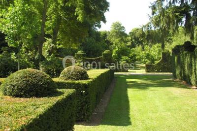 Miniature Location salle Triguères (Loiret) - Manoir du Grand Courtoiseau et ses Jardins Remarquables #15 Vaisselier rouge avec portes vitrées, contenant des verres, plats, bols et assiettes en céramique et en métal.