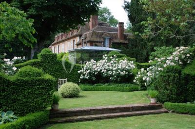 Miniature Location salle Triguères (Loiret) - Manoir du Grand Courtoiseau et ses Jardins Remarquables #7 Vaisselier rouge avec portes vitrées, contenant des verres, plats, bols et assiettes en céramique et en métal.