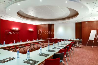 Façade moderne d'un bâtiment nommé ’Hôtel d'Entreprises Colisée’, entouré de verdure sous un ciel bleu.