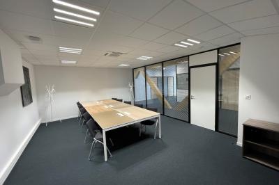 Façade moderne d'un bâtiment nommé ’Hôtel d'Entreprises Colisée’, entouré de verdure sous un ciel bleu.