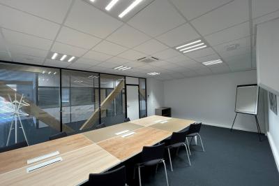 Façade moderne d'un bâtiment nommé ’Hôtel d'Entreprises Colisée’, entouré de verdure sous un ciel bleu.
