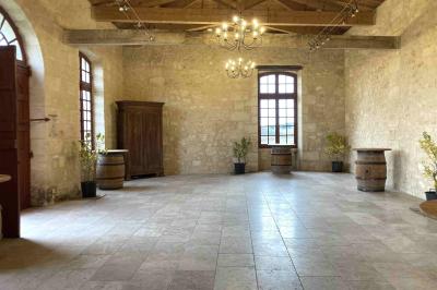 Château ancien avec deux tours rondes, vu depuis une grille en fer forgé ouverte, sous un ciel bleu.