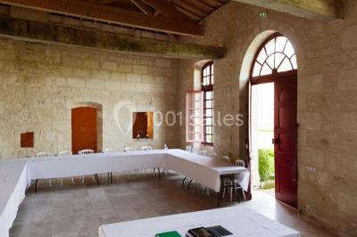 Château ancien avec deux tours rondes, vu depuis une grille en fer forgé ouverte, sous un ciel bleu.