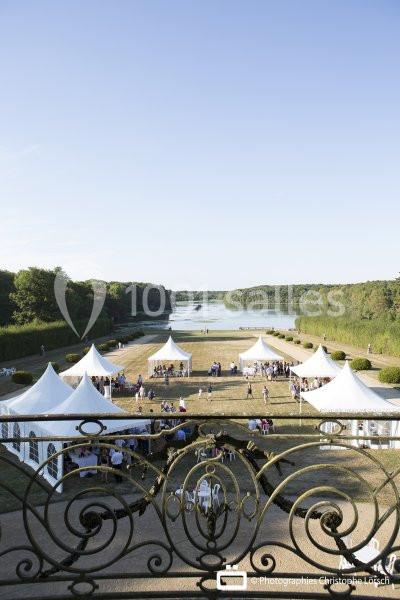 Vue d'ensemble d'un événement en plein air avec des tentes blanches, près d'un lac entouré de verdure.