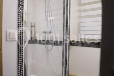 Piscine extérieure avec baigneurs, entourée de bâtiments en bois et de montagnes verdoyantes en arrière-plan.