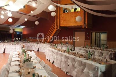 Piscine extérieure avec baigneurs, entourée de bâtiments en bois et de montagnes verdoyantes en arrière-plan.