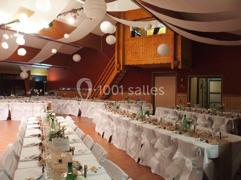 Salle de réception décorée avec des tables dressées, nappes blanches et suspensions en papier blanc au plafond.