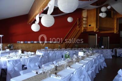 Piscine extérieure avec baigneurs, entourée de bâtiments en bois et de montagnes verdoyantes en arrière-plan.