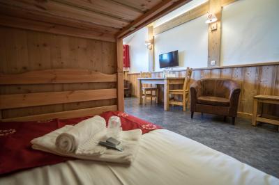 Piscine extérieure avec baigneurs, entourée de bâtiments en bois et de montagnes verdoyantes en arrière-plan.