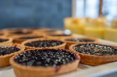 Piscine extérieure avec baigneurs, entourée de bâtiments en bois et de montagnes verdoyantes en arrière-plan.