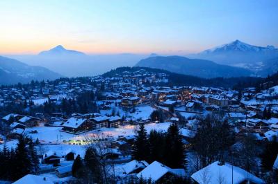 Piscine extérieure avec baigneurs, entourée de bâtiments en bois et de montagnes verdoyantes en arrière-plan.