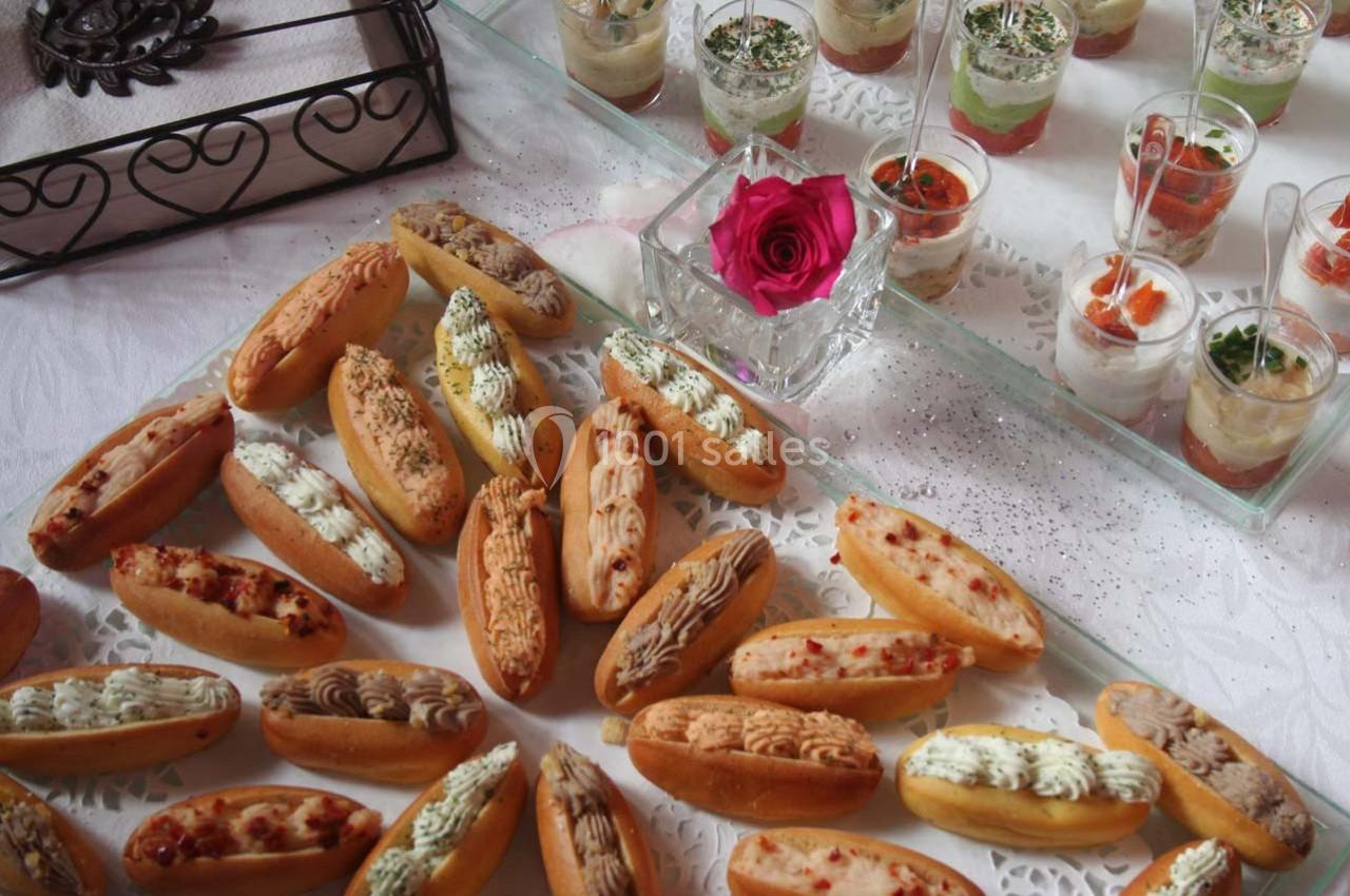 Plateau de petits éclairs salés et verrines colorées disposés sur une table décorée avec une rose.