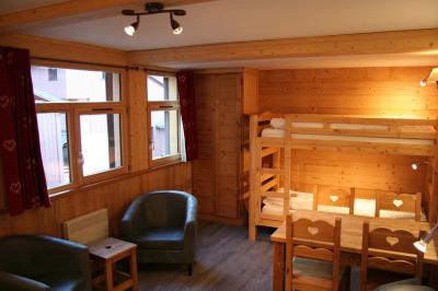 Piscine extérieure avec baigneurs, entourée de bâtiments en bois et de montagnes verdoyantes en arrière-plan.