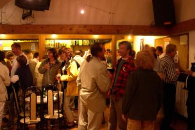 Piscine extérieure avec baigneurs, entourée de bâtiments en bois et de montagnes verdoyantes en arrière-plan.