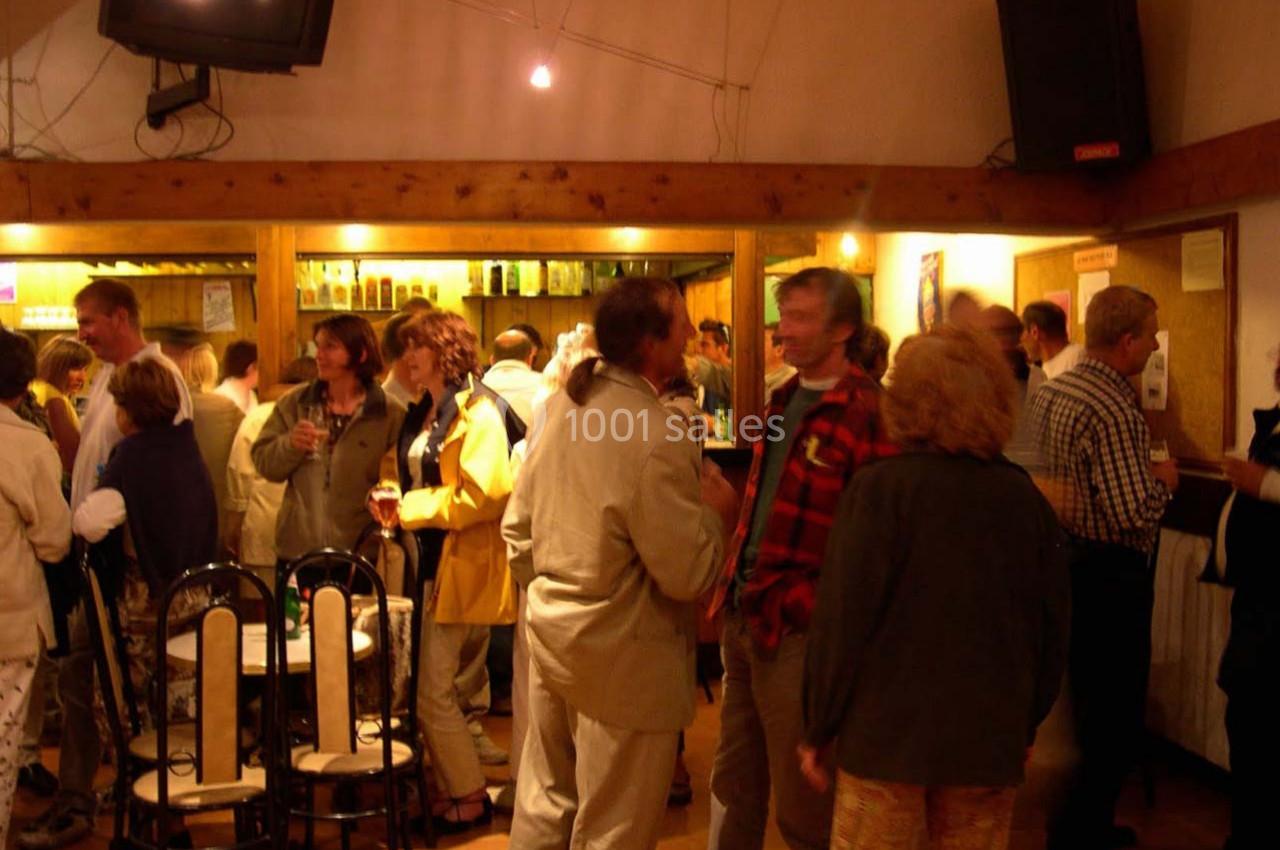 Des personnes discutent et se rassemblent dans un bar ou une salle conviviale avec un éclairage tamisé.