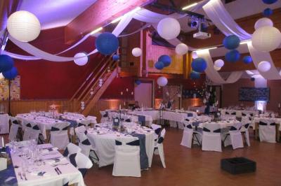 Piscine extérieure avec baigneurs, entourée de bâtiments en bois et de montagnes verdoyantes en arrière-plan.