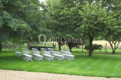Voiture ancienne blanche décorée de fleurs, stationnée devant un bâtiment en pierre avec un toit en ardoise.