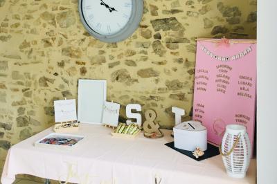 Voiture ancienne blanche décorée de fleurs, stationnée devant un bâtiment en pierre avec un toit en ardoise.