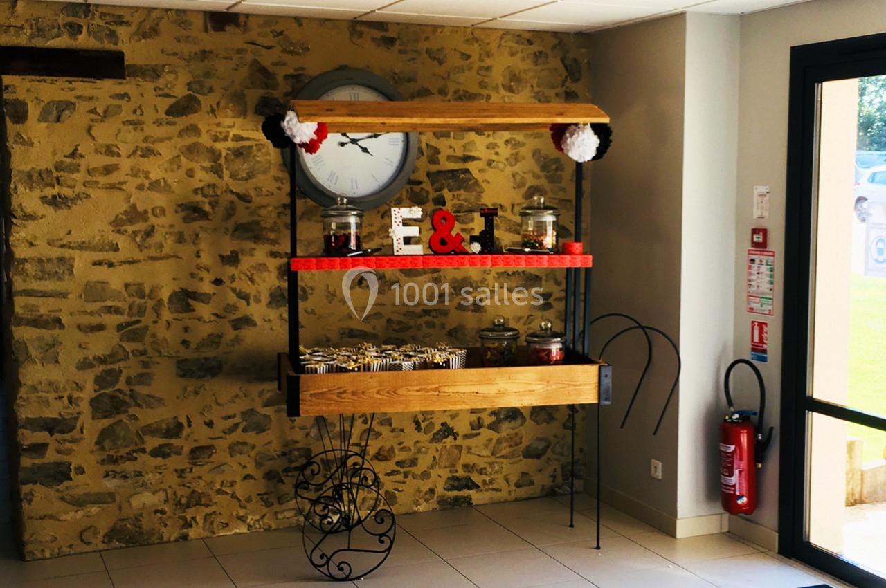 Table décorative avec des bonbonnières, des lettres ’E & T’ et des friandises, placée devant un mur en pierre.