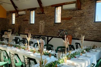 Voiture ancienne blanche décorée de fleurs, stationnée devant un bâtiment en pierre avec un toit en ardoise.