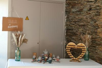 Voiture ancienne blanche décorée de fleurs, stationnée devant un bâtiment en pierre avec un toit en ardoise.