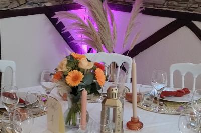 Voiture ancienne blanche décorée de fleurs, stationnée devant un bâtiment en pierre avec un toit en ardoise.