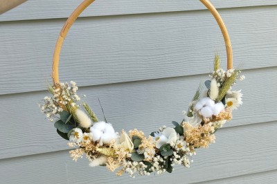 Voiture ancienne blanche décorée de fleurs, stationnée devant un bâtiment en pierre avec un toit en ardoise.