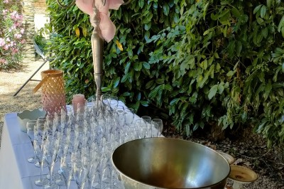 Voiture ancienne blanche décorée de fleurs, stationnée devant un bâtiment en pierre avec un toit en ardoise.