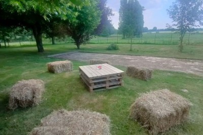 Voiture ancienne blanche décorée de fleurs, stationnée devant un bâtiment en pierre avec un toit en ardoise.