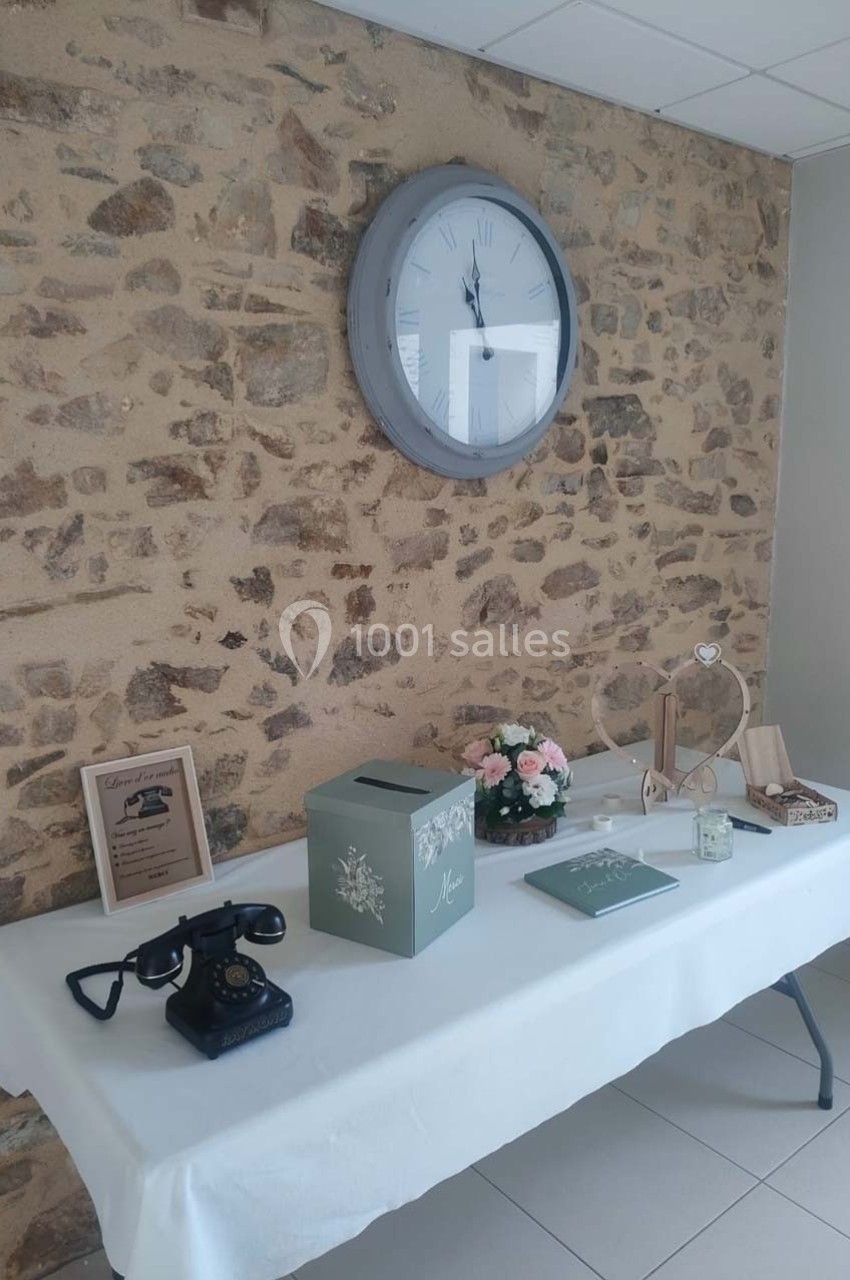 Table décorée avec une boîte à lettres, un téléphone vintage, des fleurs et des objets sur fond de mur en pierre.