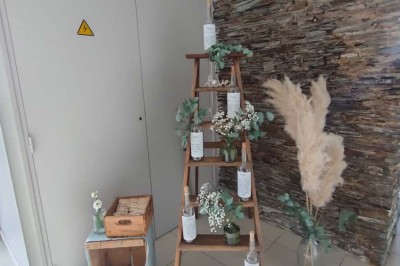 Voiture ancienne blanche décorée de fleurs, stationnée devant un bâtiment en pierre avec un toit en ardoise.