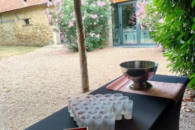 Voiture ancienne blanche décorée de fleurs, stationnée devant un bâtiment en pierre avec un toit en ardoise.