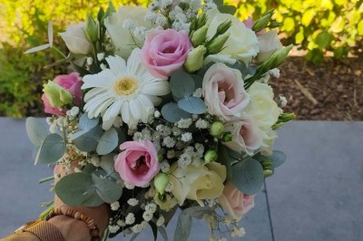 Voiture ancienne blanche décorée de fleurs, stationnée devant un bâtiment en pierre avec un toit en ardoise.