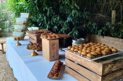 Voiture ancienne blanche décorée de fleurs, stationnée devant un bâtiment en pierre avec un toit en ardoise.